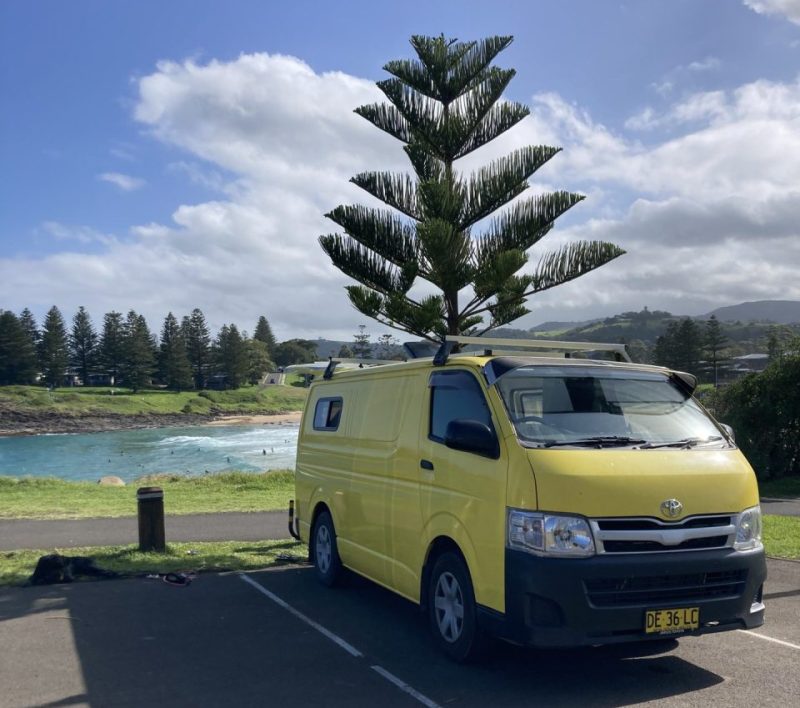 Yellow campervan located at the road trip destination at a beautiful beach in Kiama.